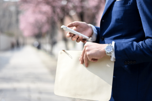 Homme habillé en costard avec un portable et une montre Rolex