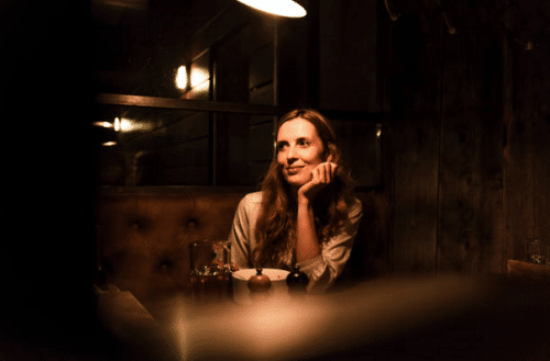 Femme sur une banquette dans un bar à la lumière tamisée